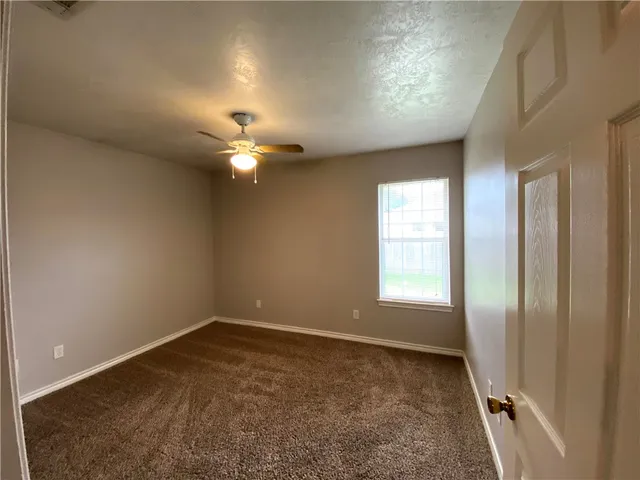 en empty room with windows and ceiling fan