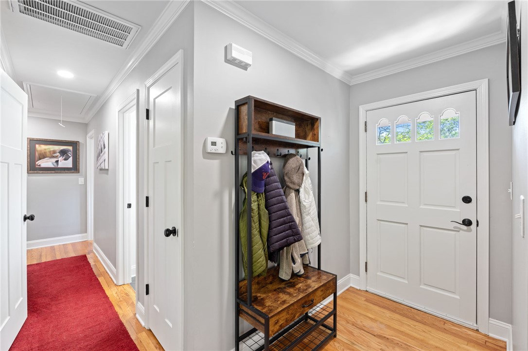209 Manley Drive Clemson, SC 29631 - Photo 21 of 44 This inviting entry hallway features warm wood flooring and classic crown molding, leading to a pristine white door.