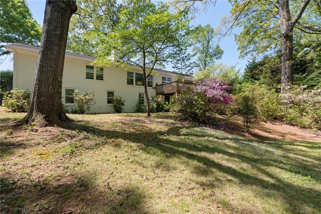 209 Manley Drive Clemson, SC 29631 - Photo 39 of 44 This tranquil yard features a spacious deck, mature trees, and vibrant landscaping, perfect for outdoor living.