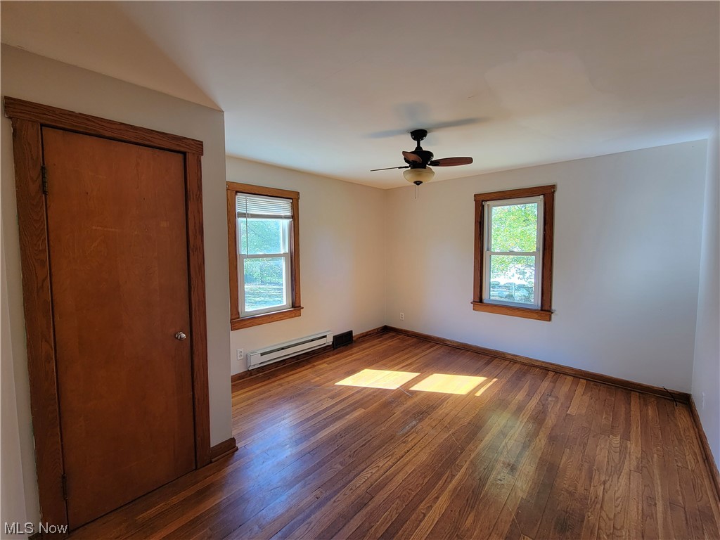 4506 Sandy Lake Road Ravenna, OH 44266 - Photo 13 of 32 Unfurnished bedroom featuring dark hardwood flooring, ceiling fan, and a baseboard heating unit