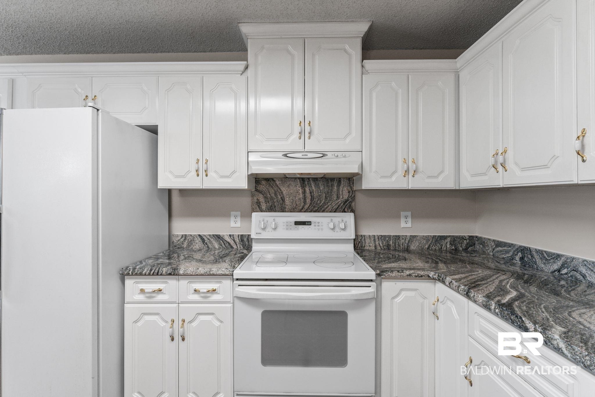 888 Mobile Cut-Off Road St. Stephens, AL 36569 - Photo 15 of 54 Kitchen with white appliances, white cabinetry, under cabinet range hood, dark stone countertops, and a textured ceiling