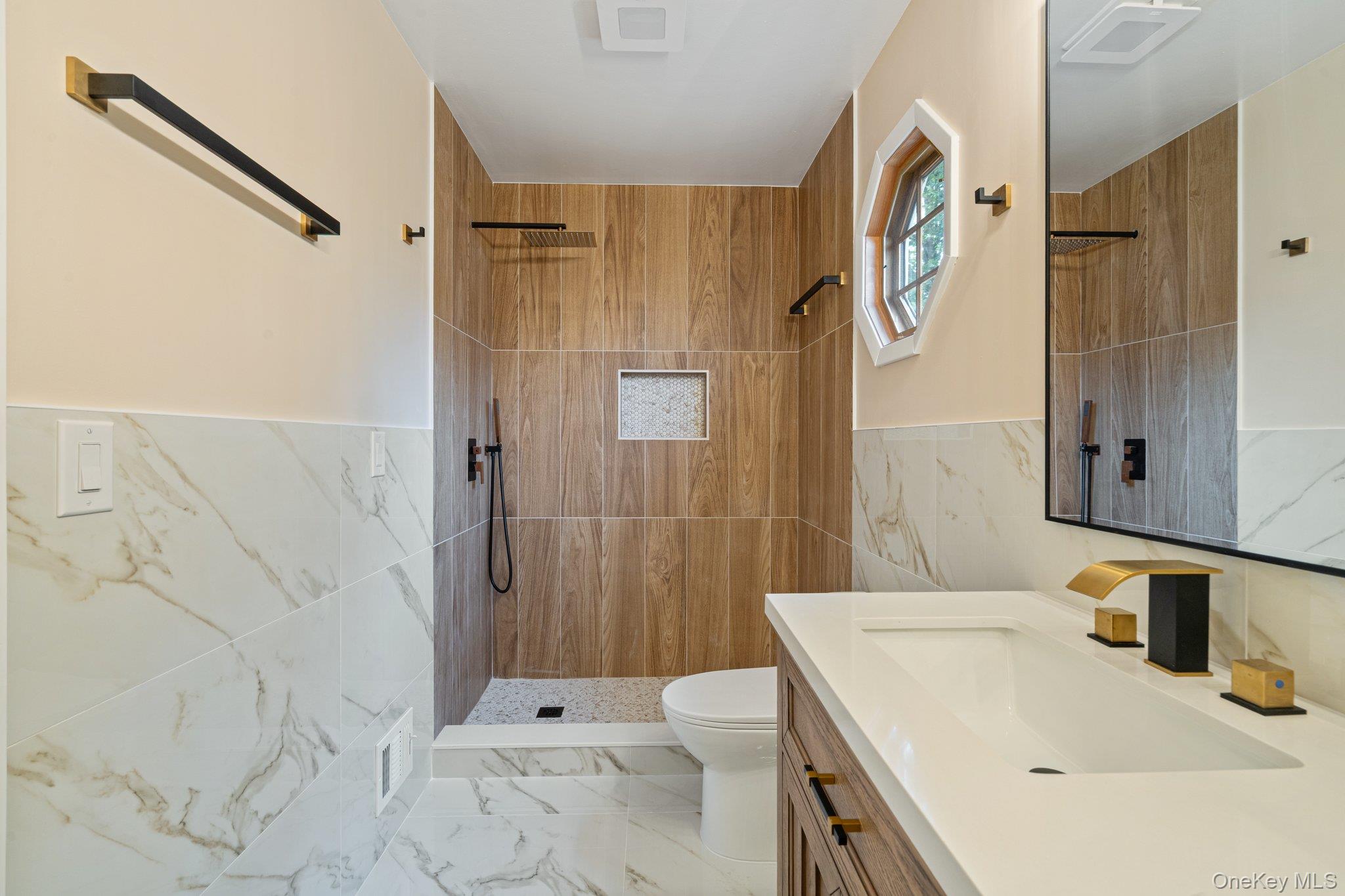 6 Doe Path Coram, NY 11727 - Photo 21 of 48 Full bath with tile walls, marble finish floors, a tile shower, vanity, and wainscoting