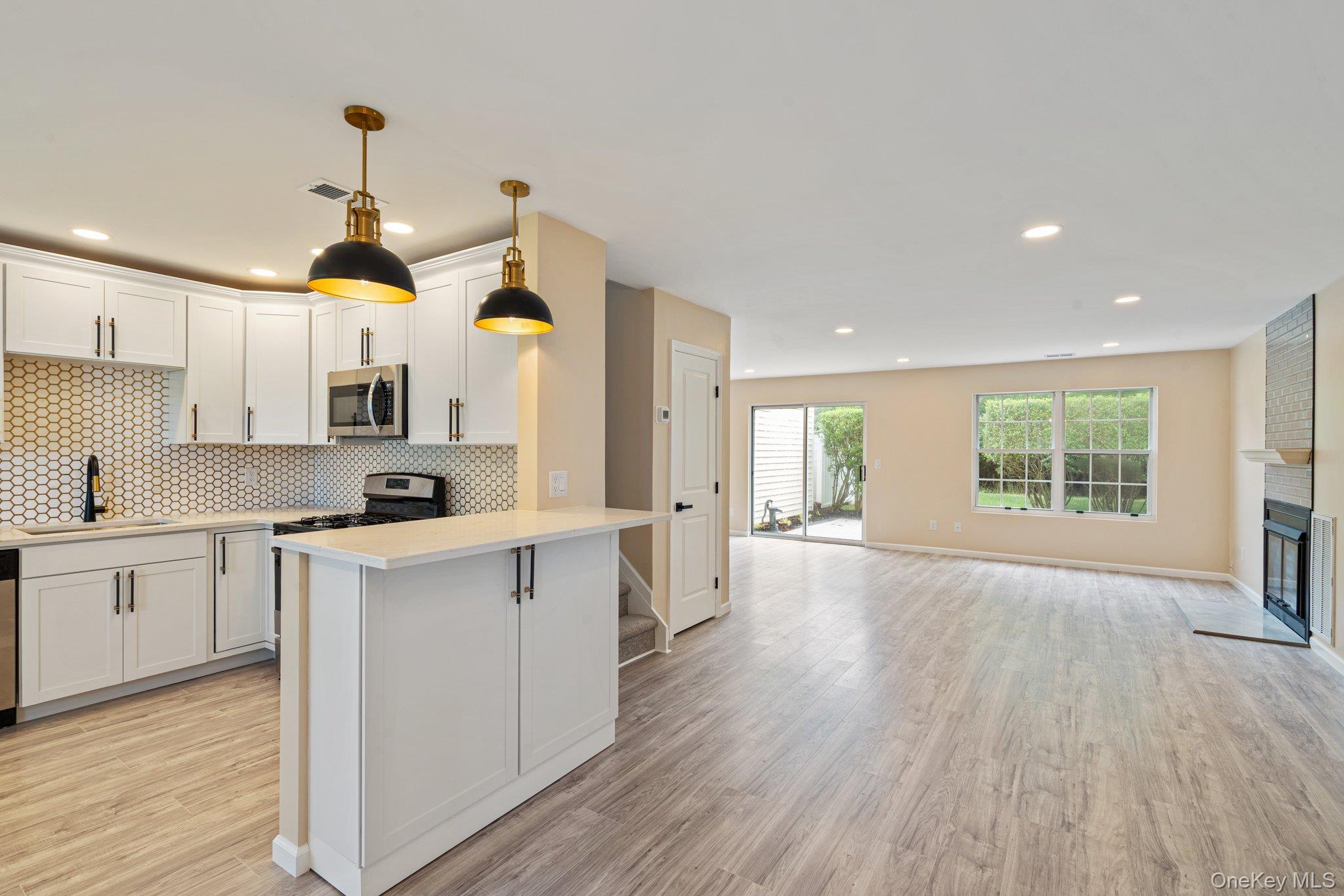 6 Doe Path Coram, NY 11727 - Photo 48 of 48 Kitchen featuring stainless steel microwave, light countertops, light wood finished floors, tasteful backsplash, and open floor plan