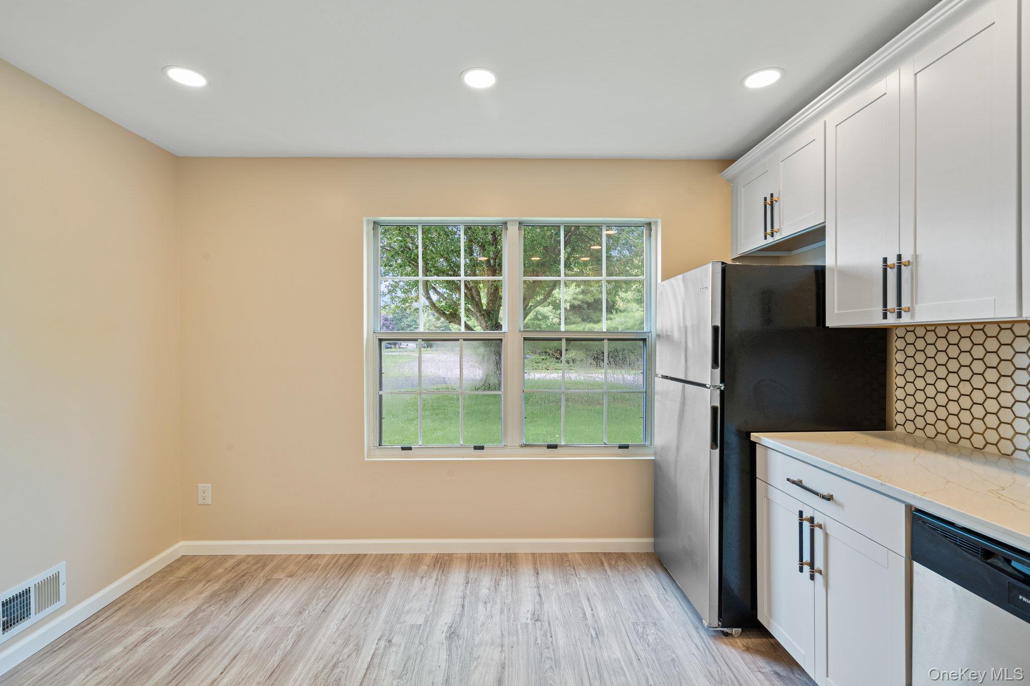 6 Doe Path Coram, NY 11727 - Photo 7 of 48 Kitchen with stainless steel appliances, decorative backsplash, light wood finished floors, white cabinetry, and light stone countertops