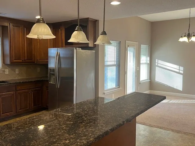 an empty room with a chandelier fan and windows