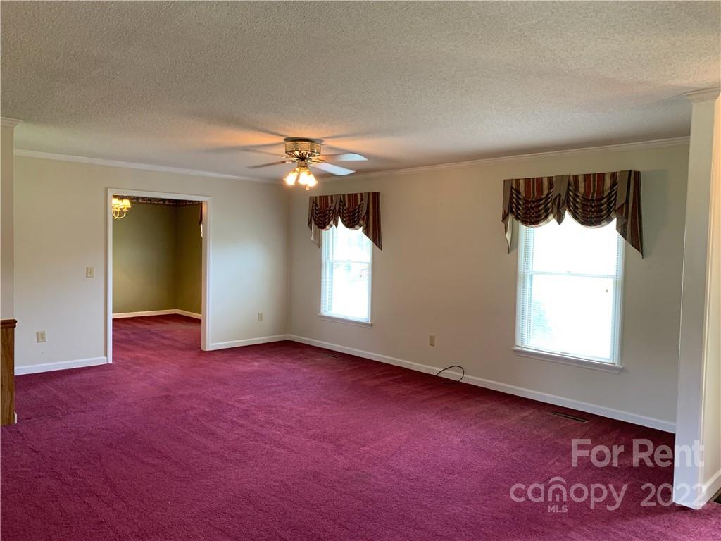 954 Old Charlotte Road Southwest Concord, NC 28027 - Photo 3 of 15 an empty room with windows and chandelier fan