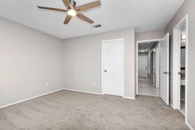 an empty room with closet and a ceiling fan