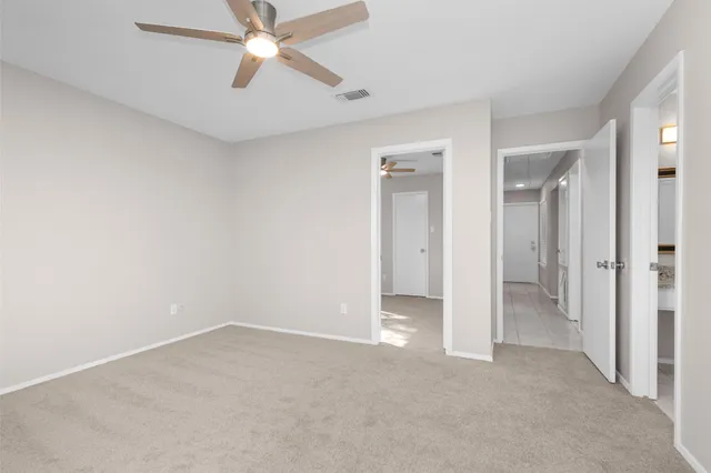 an empty room with closet and a ceiling fan