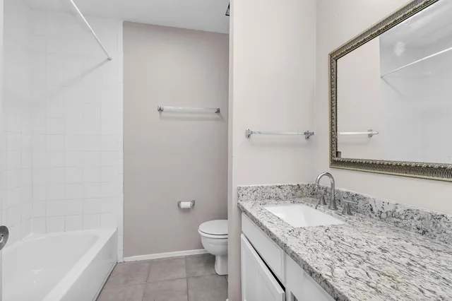 a bathroom with a granite countertop sink a toilet and bathtub