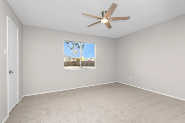 an empty room with a ceiling fan and a window
