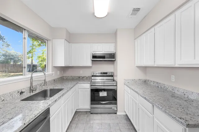 a kitchen with granite countertop a sink stove and cabinets