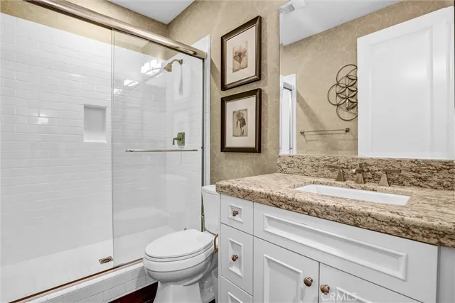 a bathroom with a granite countertop sink toilet and shower