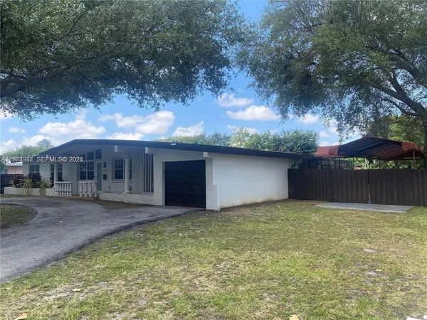 a front view of house with yard and trees in the background