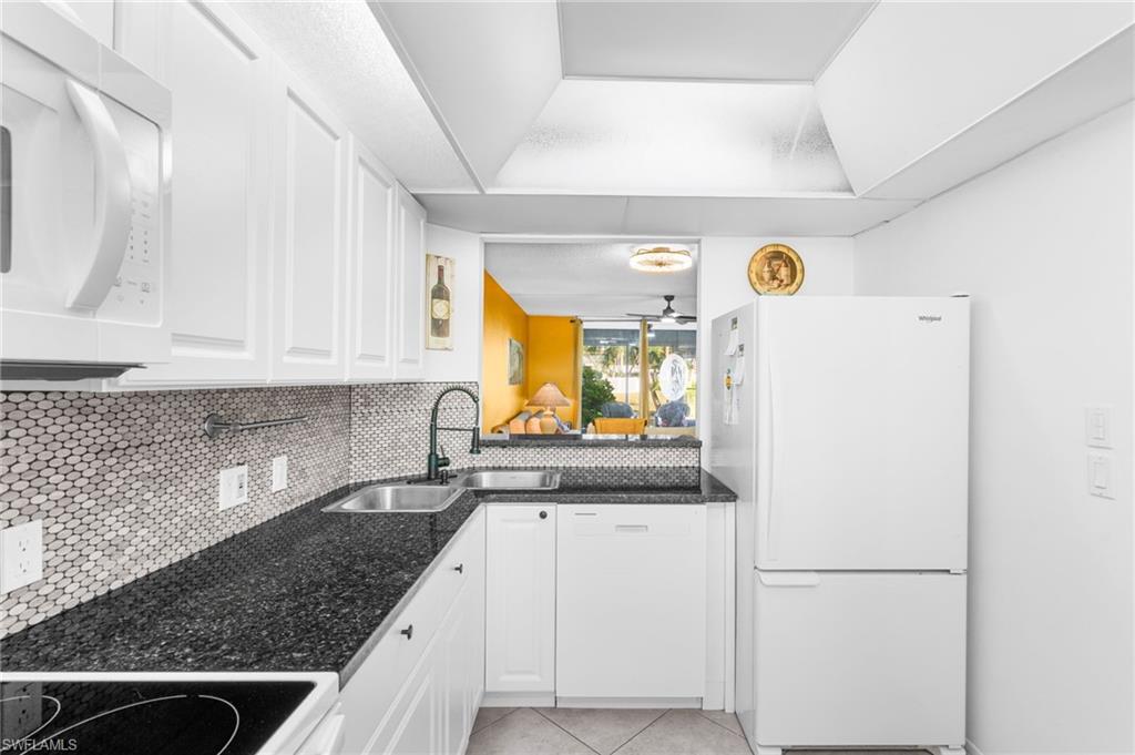 5959 Winkler Road, Unit 114 Fort Myers, FL 33919 - Photo 7 of 20 a kitchen with a refrigerator a sink and wooden cabinets