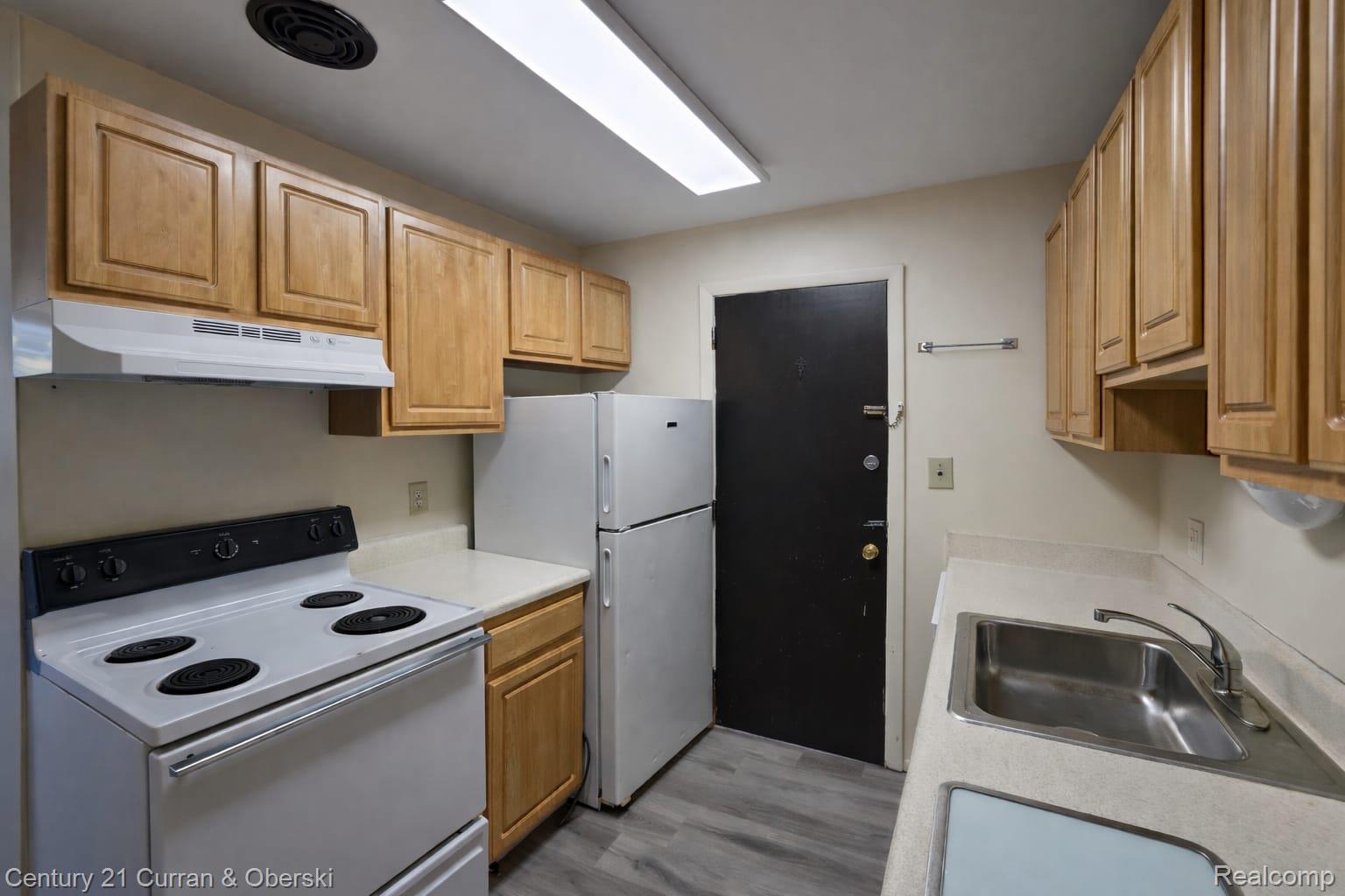 6015 Southfield Road, Unit 8 Detroit, MI 48228 - Photo 6 of 13 Kitchen with white appliances, light countertops, and light wood finished floors
