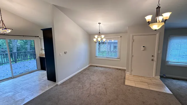 an empty room with chandelier fan and windows