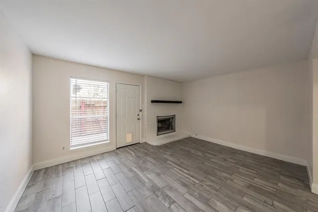 an empty room with wooden floor fireplace and windows