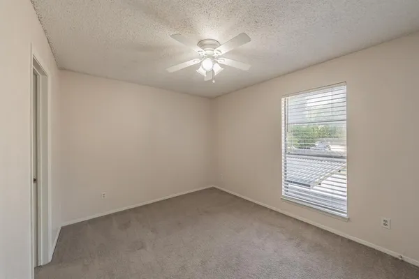 an empty room with a window and a ceiling fan