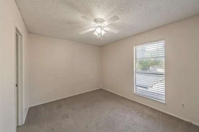 an empty room with a window and a ceiling fan