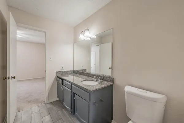 a bathroom with a granite countertop sink a toilet and a mirror