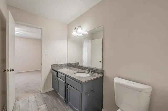 a bathroom with a granite countertop sink a toilet and a mirror