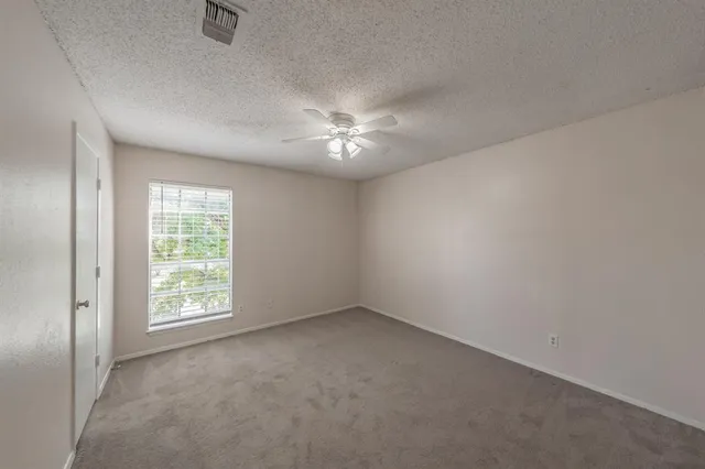 an empty room with windows and fan