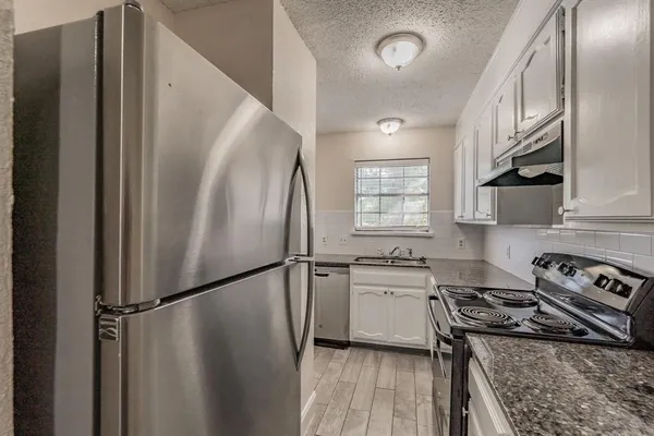 a kitchen with stainless steel appliances a refrigerator a stove a sink and a window