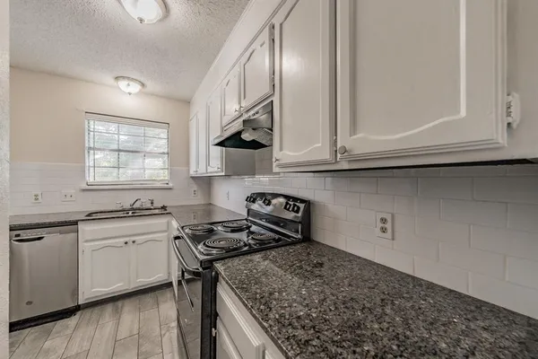 a kitchen with granite countertop a sink a stove and cabinets
