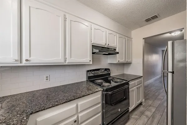 a kitchen with stainless steel appliances granite countertop white cabinets and a stove