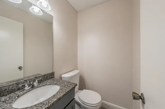 a bathroom with a granite countertop sink toilet a mirror and shower