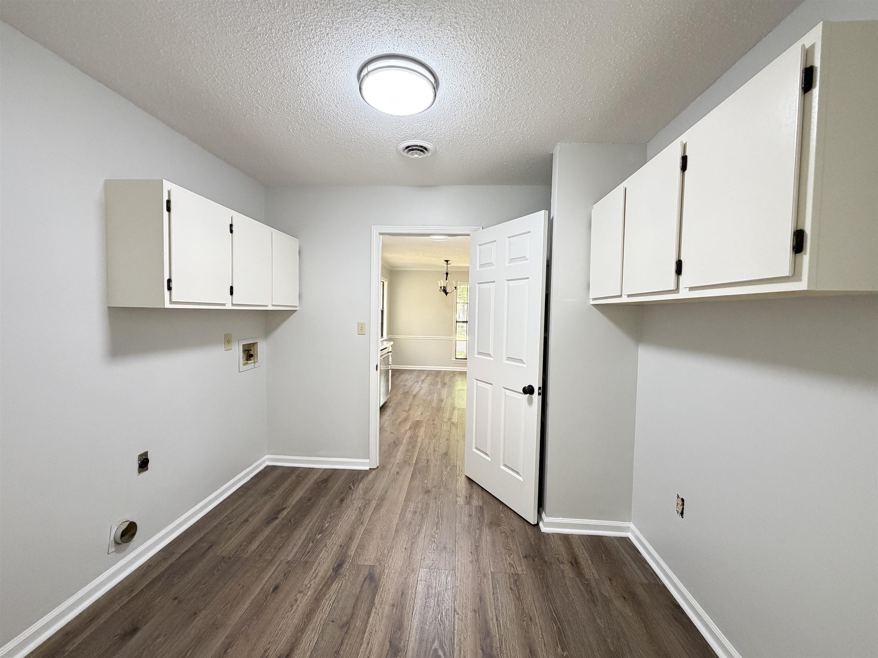 388 Park Hill Road Collierville, TN 38017 - Photo 6 of 19 Utility space featuring wood-finish flooring, white wall cabinetry, and light gray walls
