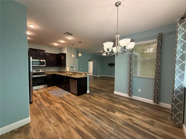 a large kitchen with kitchen island a sink stainless steel appliances and chandelier
