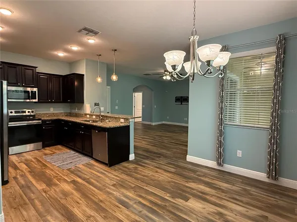a kitchen with stainless steel appliances granite countertop cabinets a refrigerator and a wooden floor