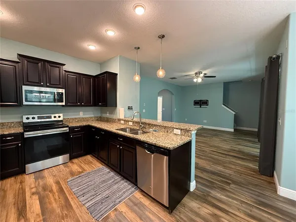 a large kitchen with stainless steel appliances granite countertop a stove and a wooden cabinets