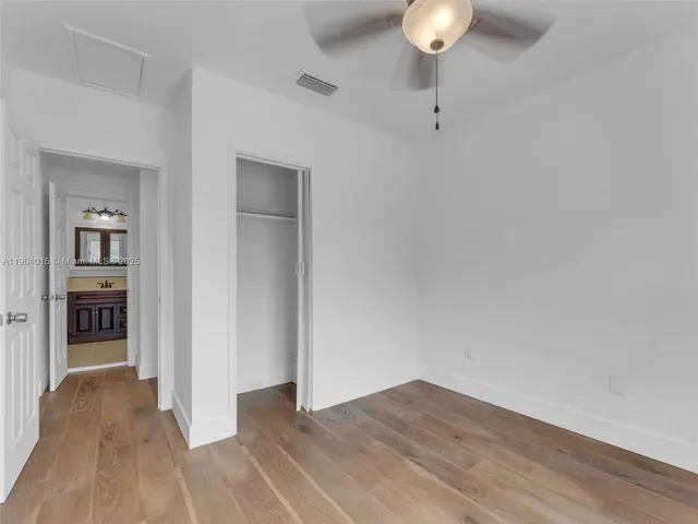 a view of empty room with wooden floor and fan