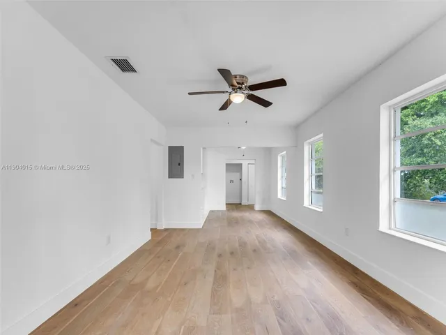 a view of empty room with wooden floor and fan