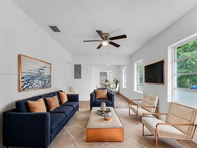 a living room with furniture a flat screen tv and a large window