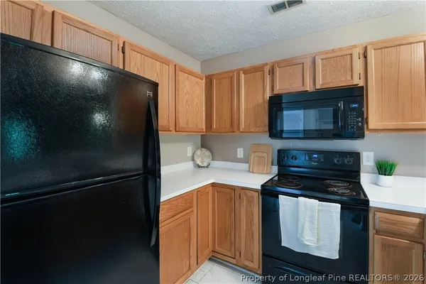 a kitchen with granite countertop a refrigerator and a stove top oven