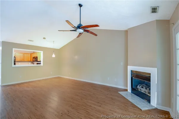 an empty room with wooden floor fan and windows