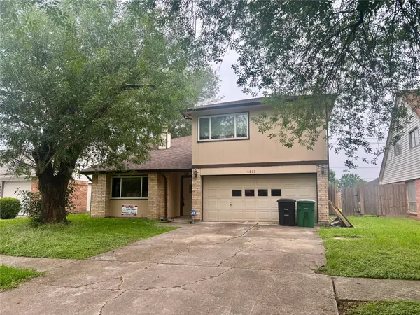 a front view of a house with a garden and tree