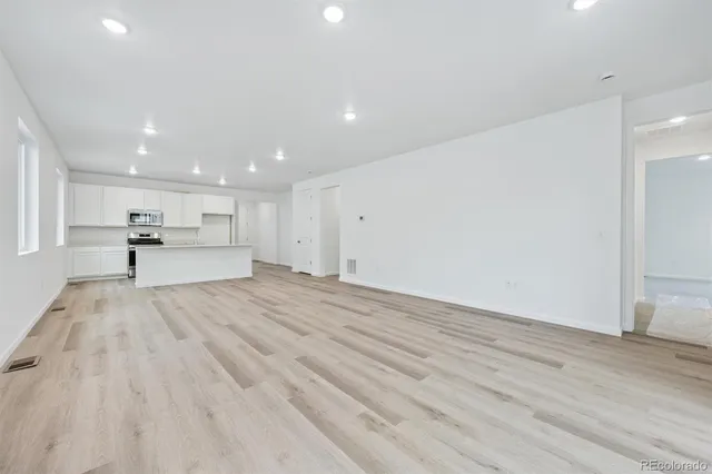 a view of kitchen with kitchen island a sink wooden floor and black appliances