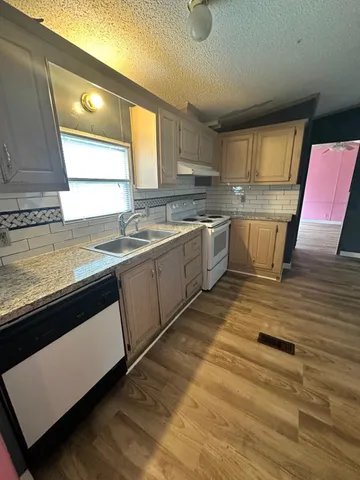 a kitchen with a sink a stove cabinets and a wooden floor