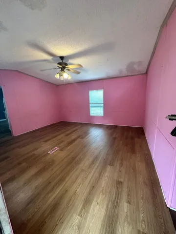 a view of an empty room and chandelier fan