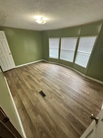 en empty room with wooden floor and windows