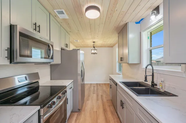 a kitchen with granite countertop a sink a stove and refrigerator