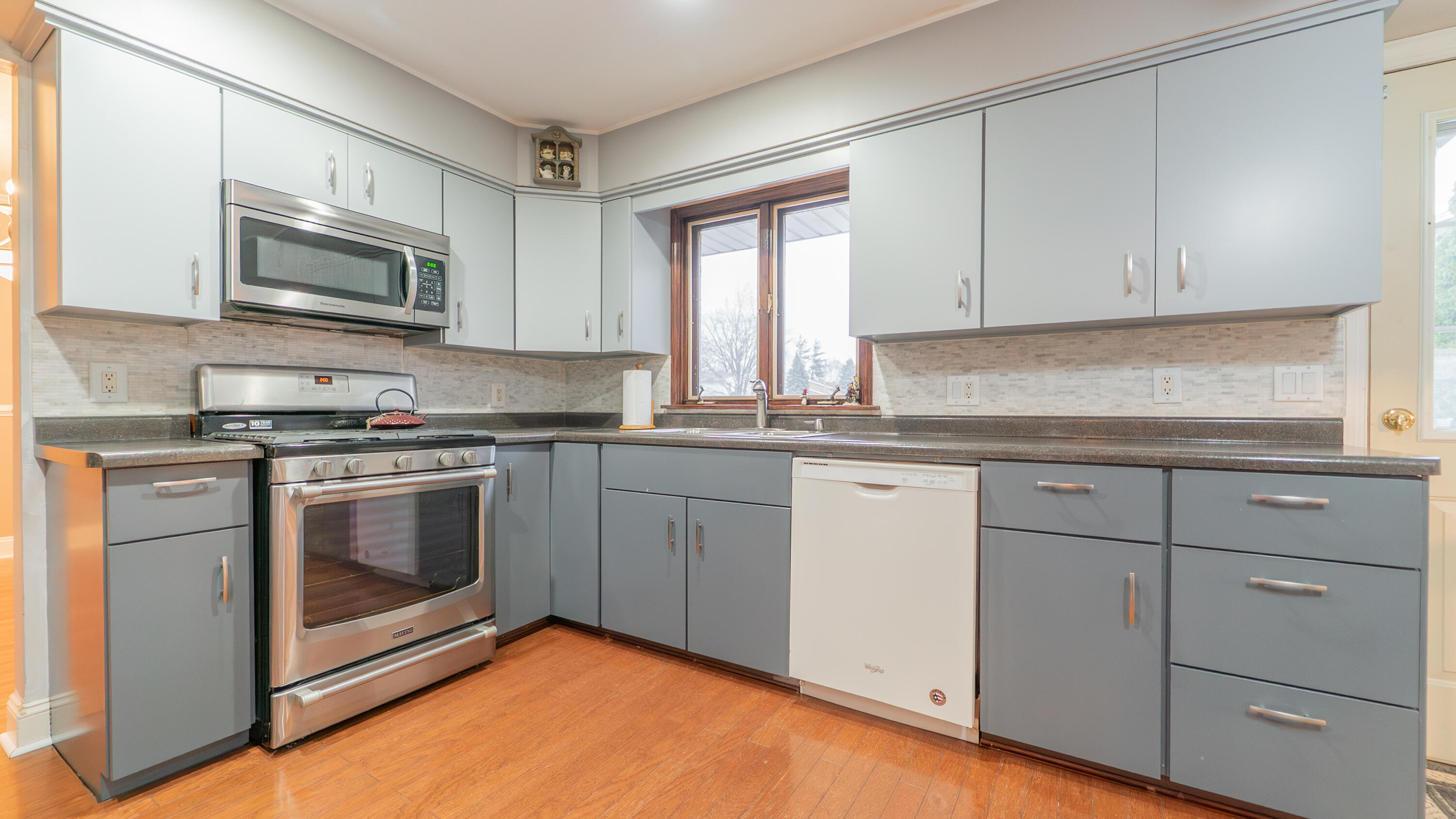 9439 Walnut Drive Munster, IN 46321 - Photo 11 of 40 a kitchen with granite countertop white cabinets stainless steel appliances a sink and a window