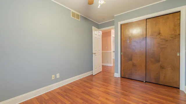 a view of an empty room with wooden floor and bathroom