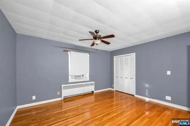 a view of empty room with wooden floor and ceiling fan