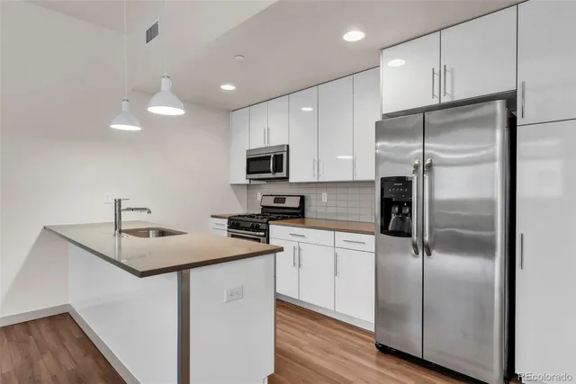 a view of kitchen with stainless steel appliances granite countertop white cabinets and wooden floor