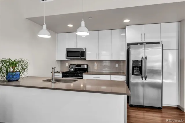 a kitchen with stainless steel appliances granite countertop a refrigerator a stove a microwave and white cabinets